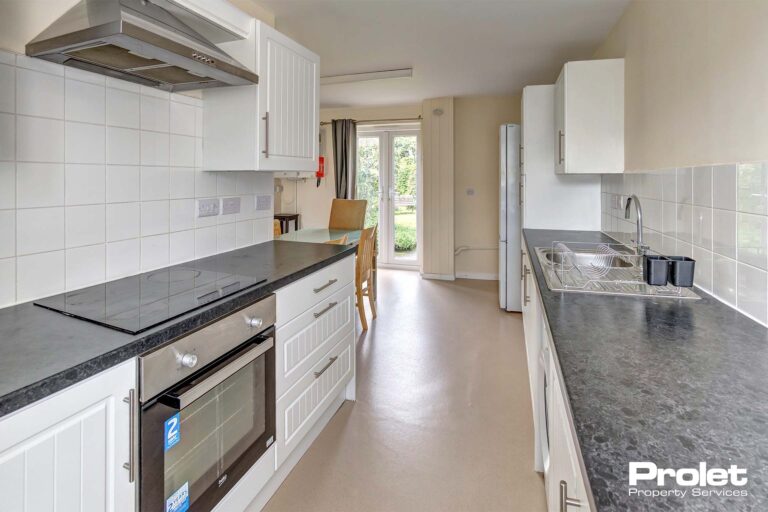 Modern kitchen with white cupboards, and black worktops