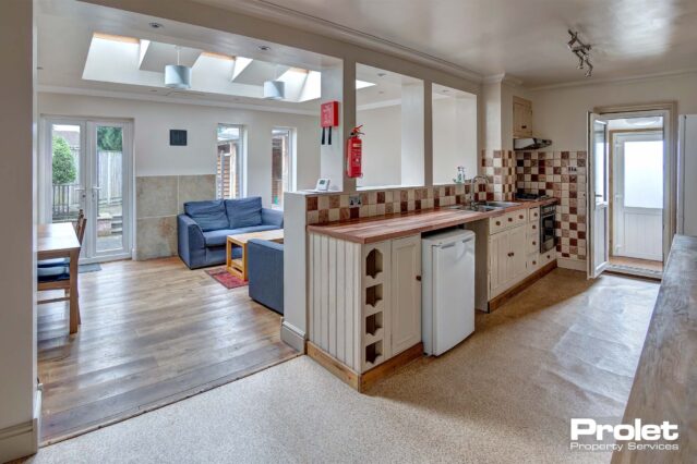 Open plan kitchen area with fitted kitchen cupboards and an under the counter fridge/freezer.