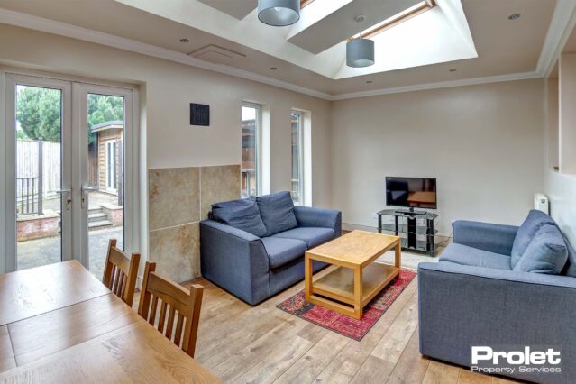 Lounge area with lino flooring, two grey fabric sofas, a wooden coffee table and a tv unit.