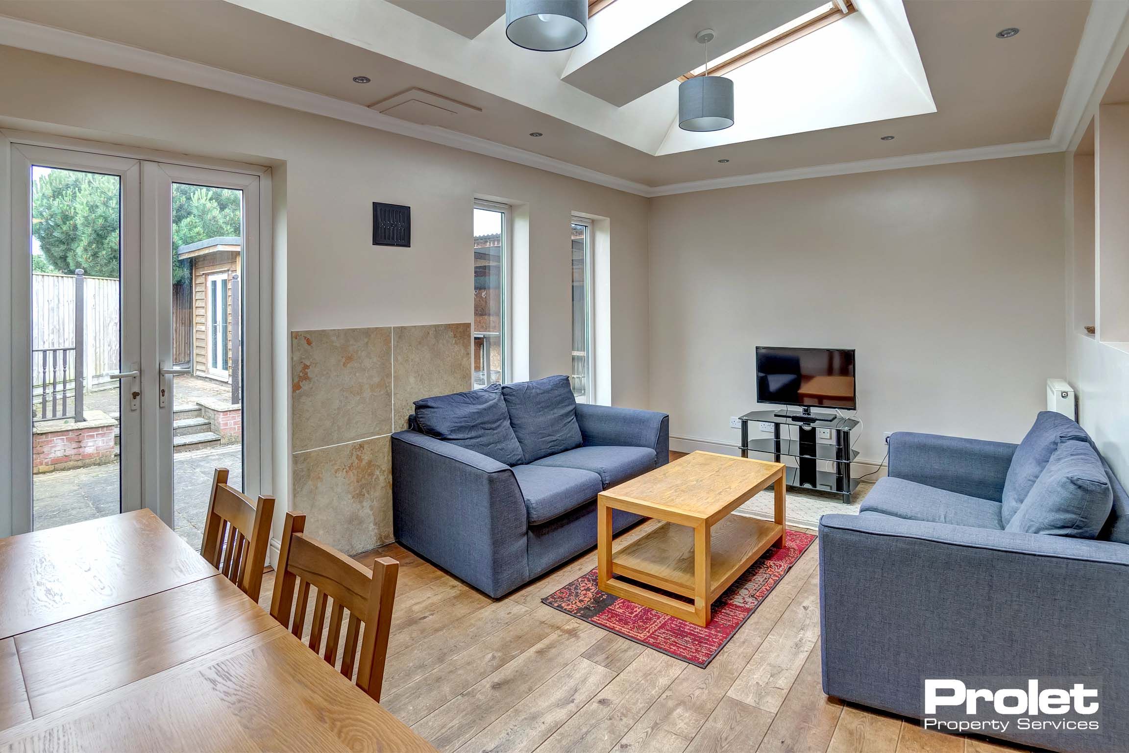 Lounge area with lino flooring, two grey fabric sofas, a wooden coffee table and a tv unit.