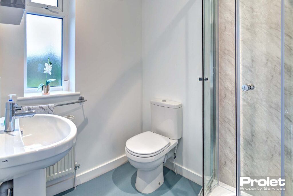 Ensuite bathroom with walk in shower with glass doors, a white toilet and sink.