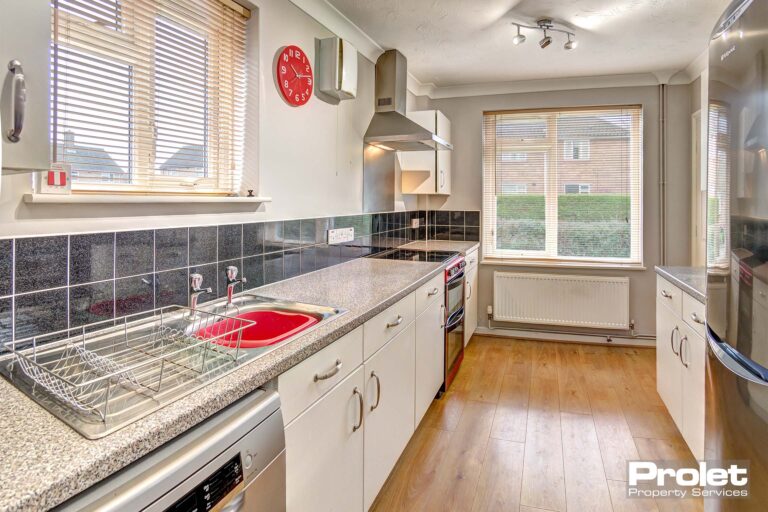 Modern kitchen with wood effect flooring, white cabinets, white worktops.
