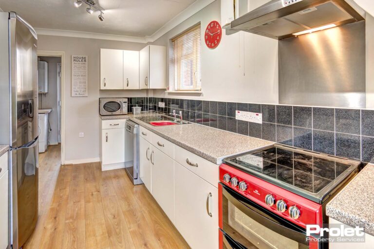 Modern kitchen with wood effect flooring, white cabinets, white worktops.