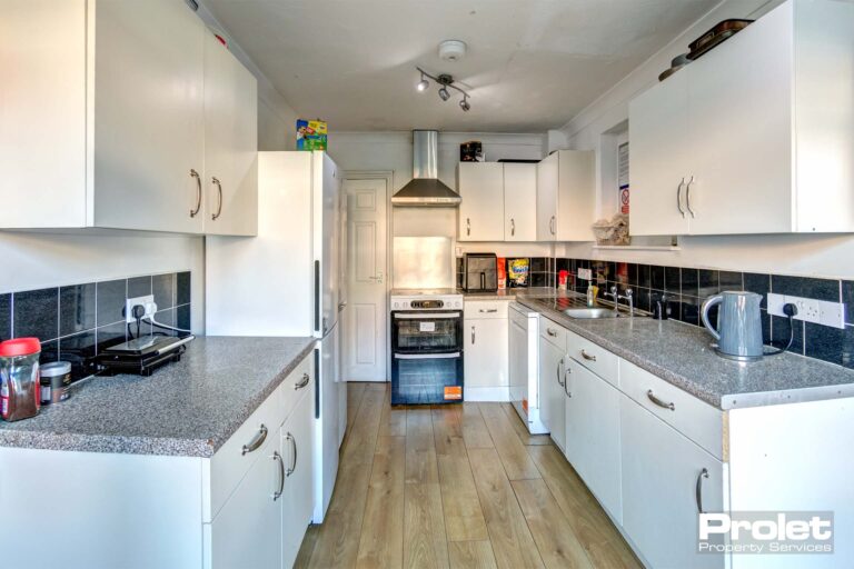 Modern kitchen with laminate flooring and white cabinets.