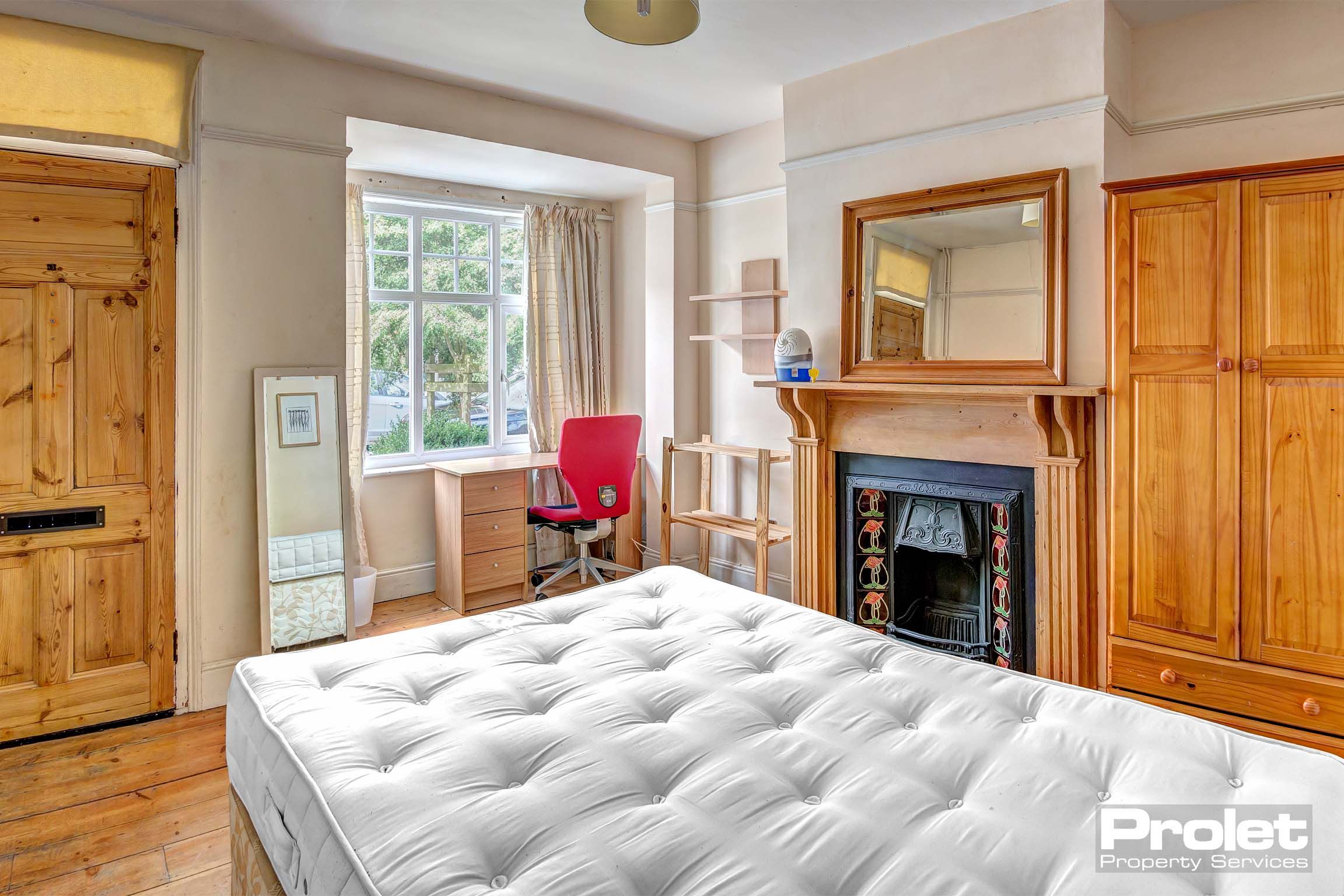 Downstairs bedroom with double bed, period fireplace, and desk