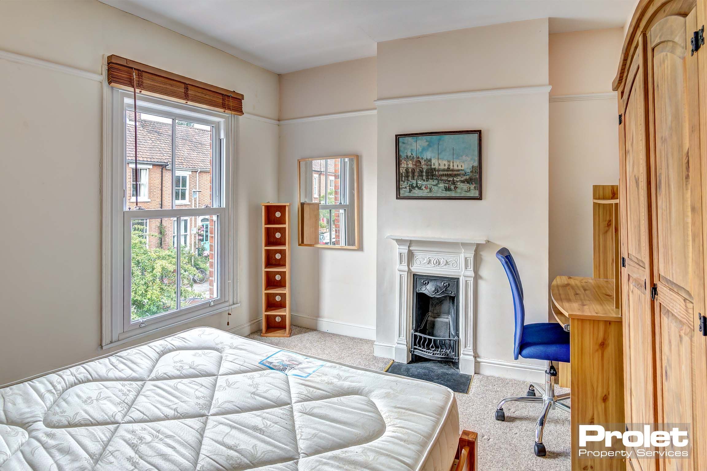 Bedroom with double bed, period fireplace, and desk