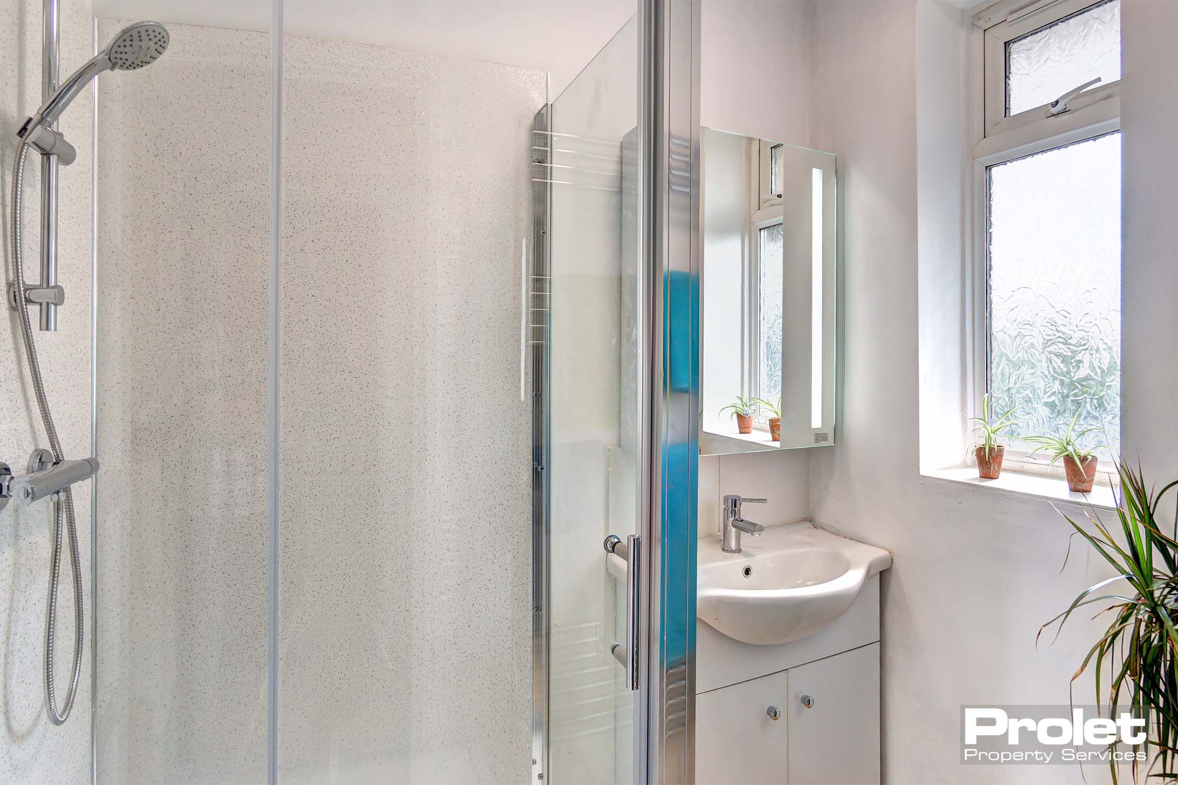 Bathroom with shower cubicle, sink, and wall mirror
