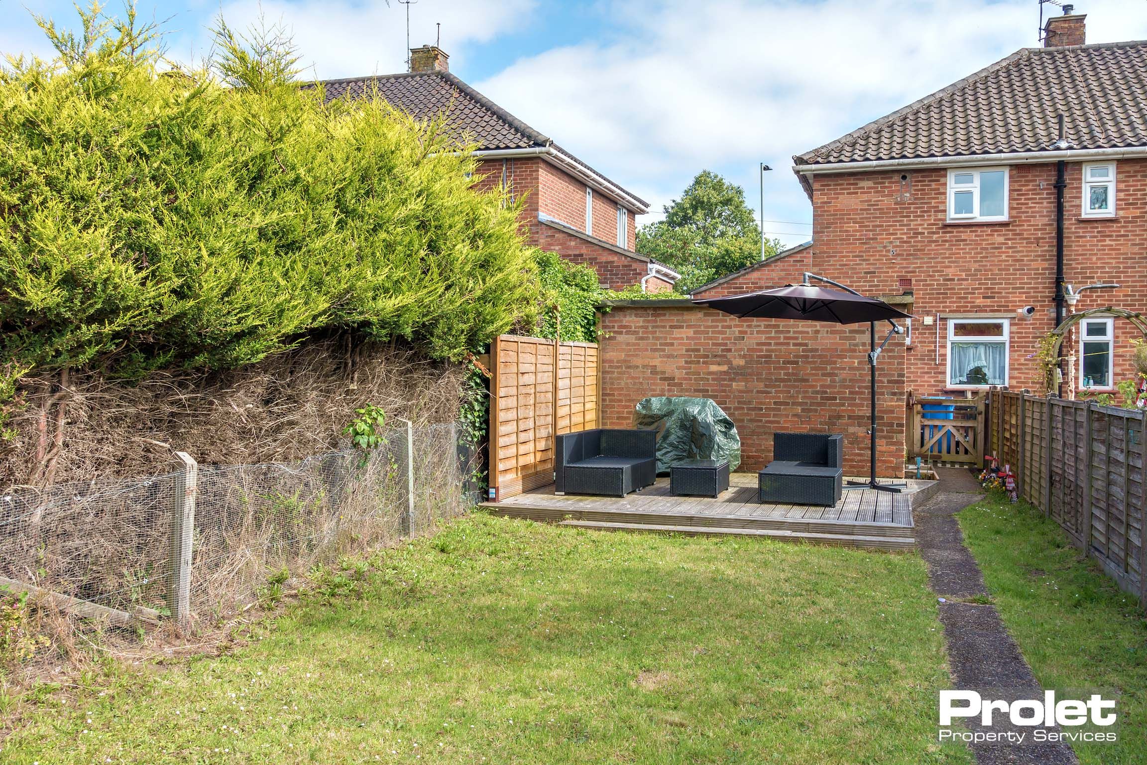 Rear garden with grass area, a pathway to the house and a patio area with outdoor seating.