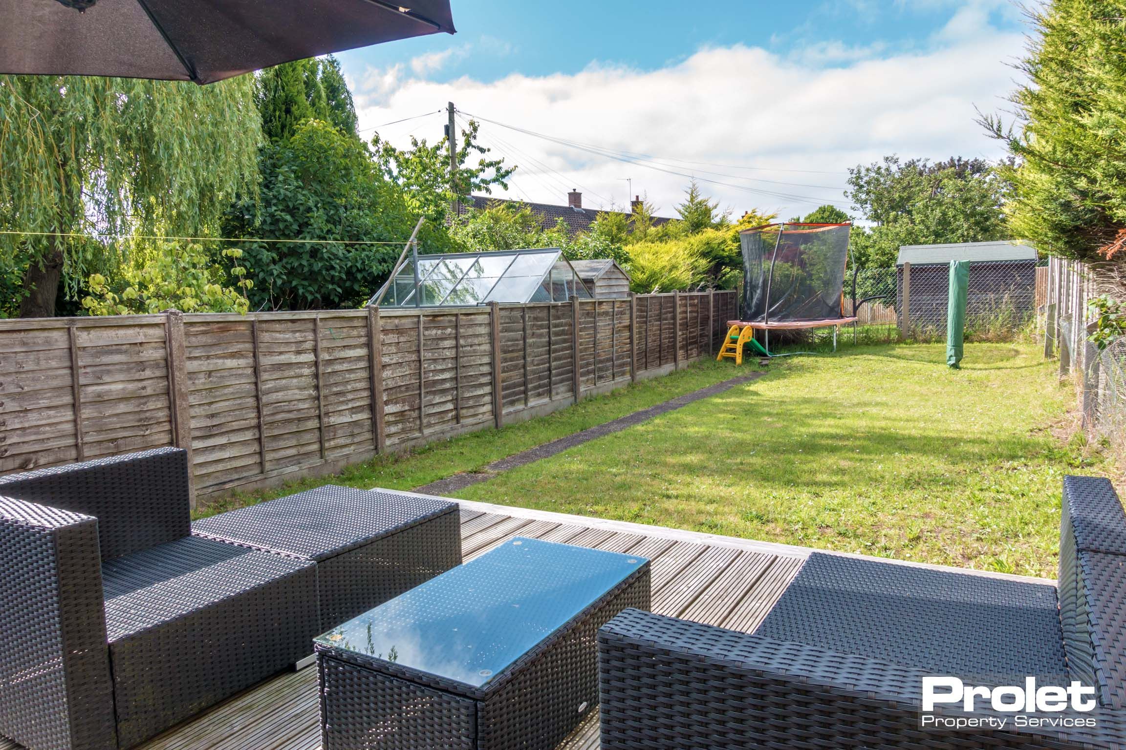 Rear garden with grass area, a patio area and modern outdoor (black weaved) seating.