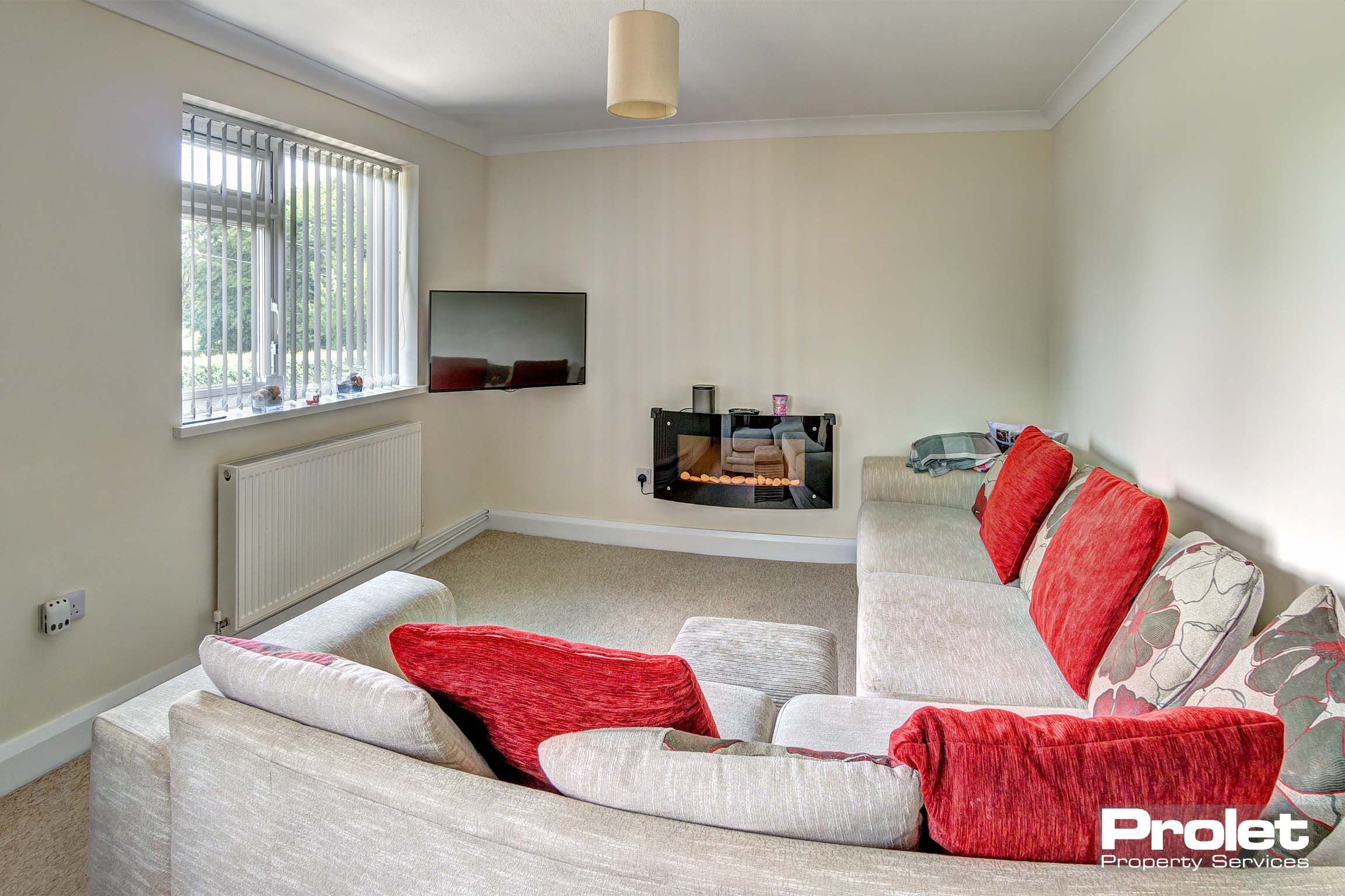 Large lounge area with large fabric corner sofa with scatter cushions and an electric fireplace.