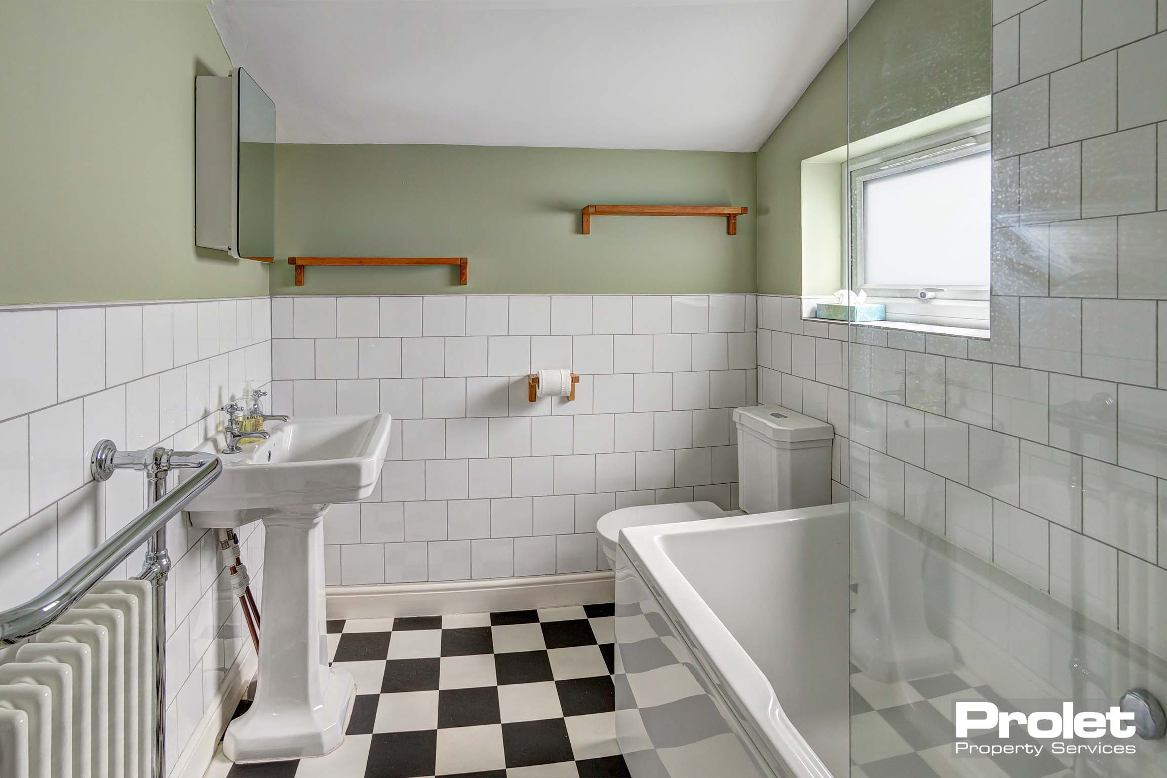 Bathroom with white suite and white tiled and painted green walls