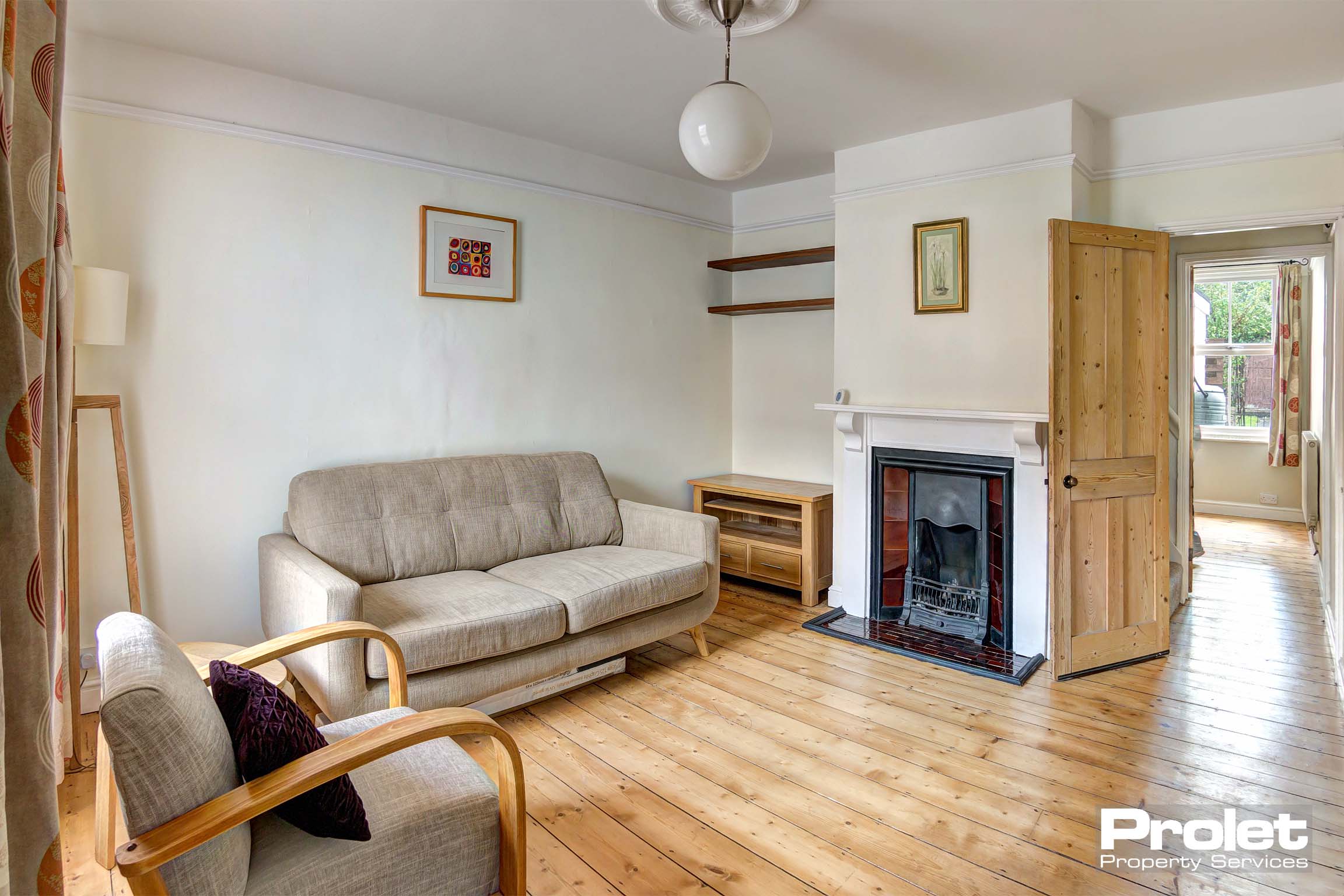 Lounge with stripped floors, sofa, chair and feature fireplace