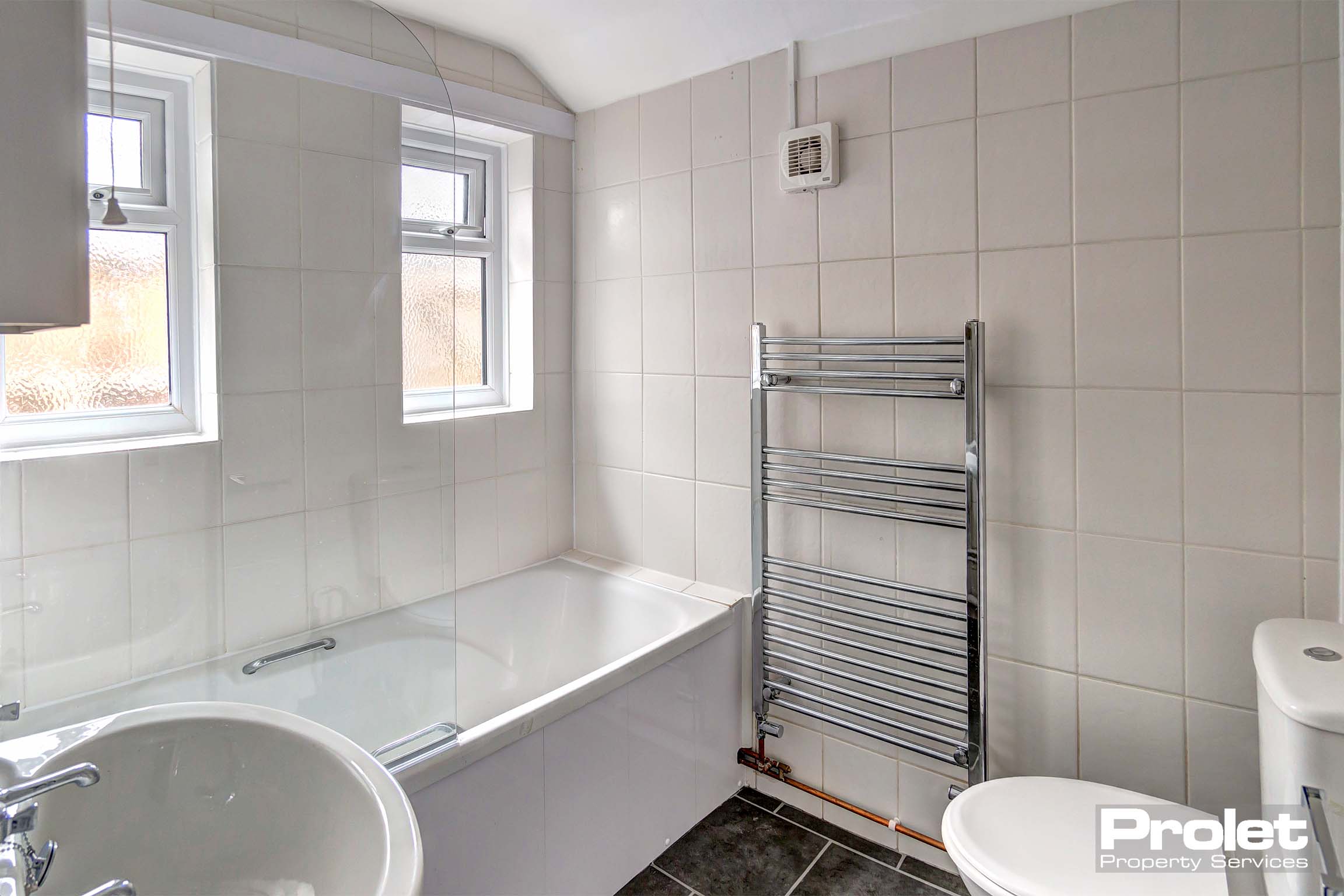 White bathroom suite with shower over bath and grey floor