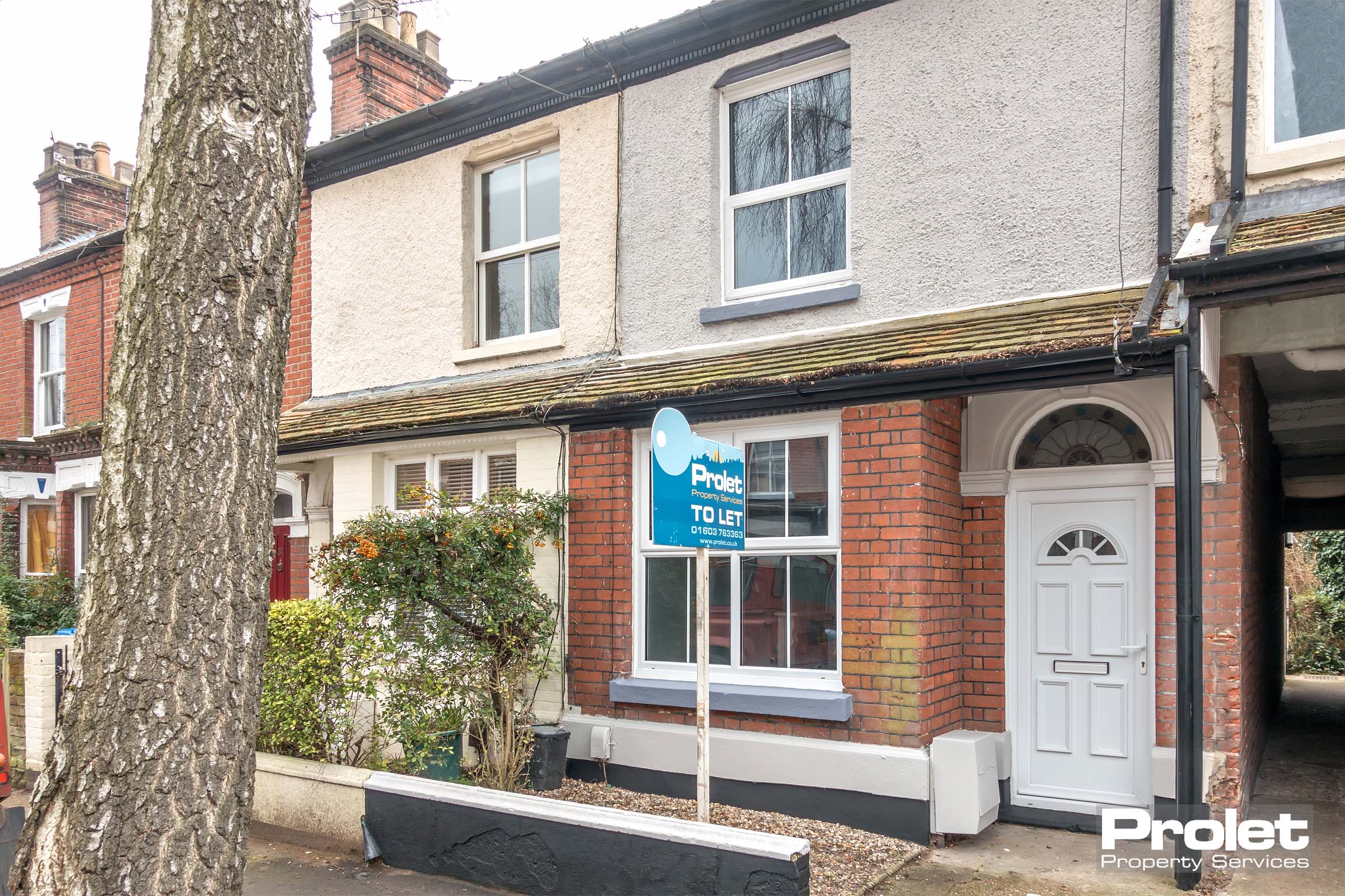 Brick house with small slabbed front garden and bay window