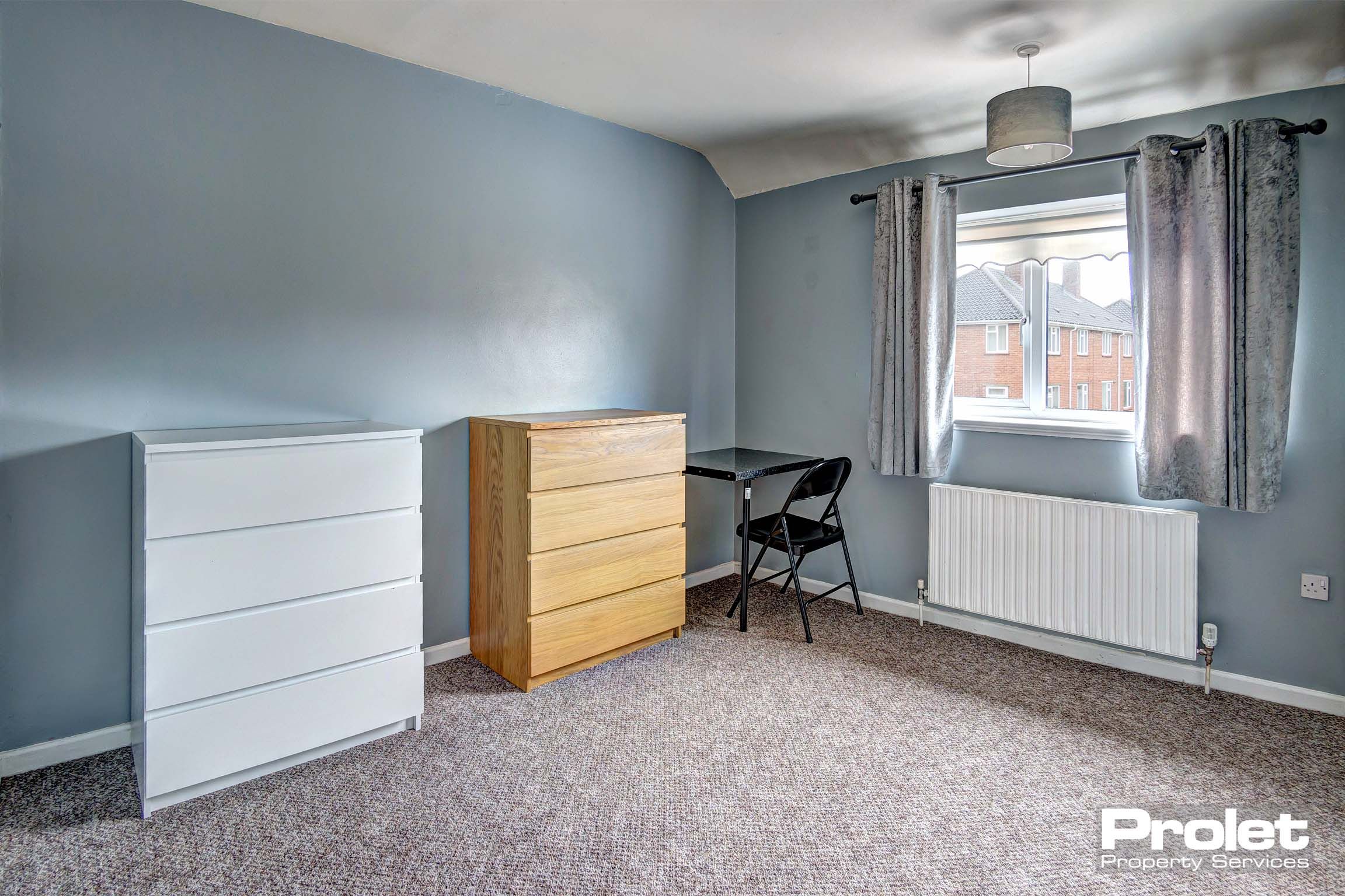 Spacious bedroom with chest of drawers and desk