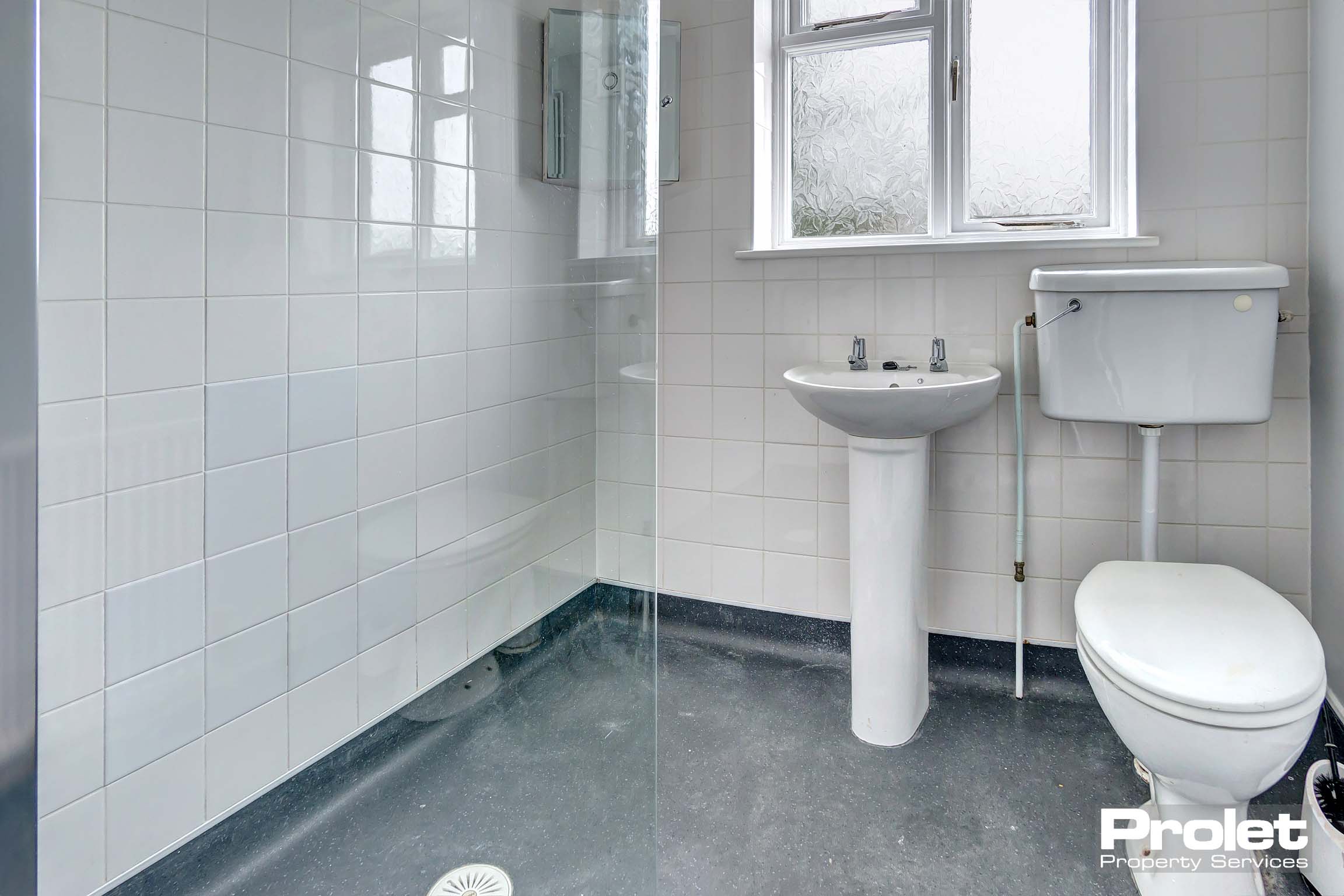 white bathroom suite with white tiled walls and grey floor