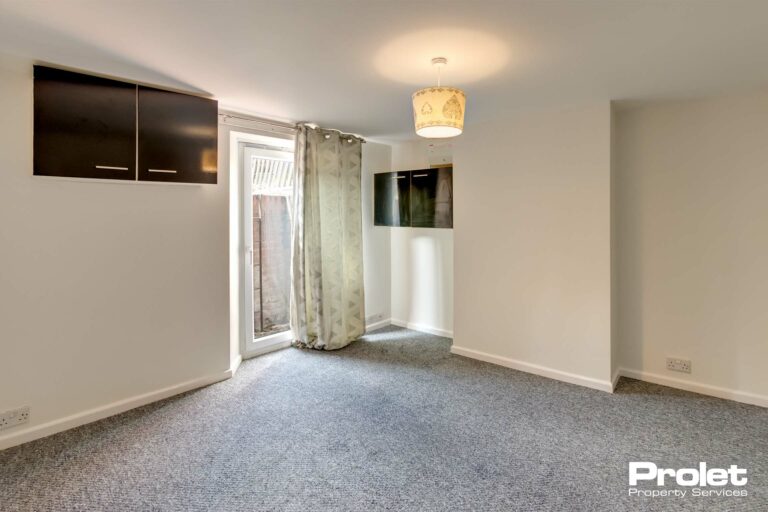 Basement room with black cabinets, white walls, and grey carpet