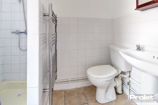 Bathroom with toilet, sink, towel warmer, and shower cubicle