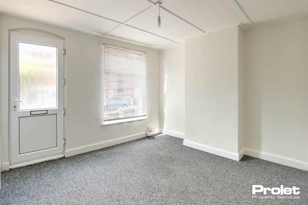 Living room painted white with a UPVC front door.