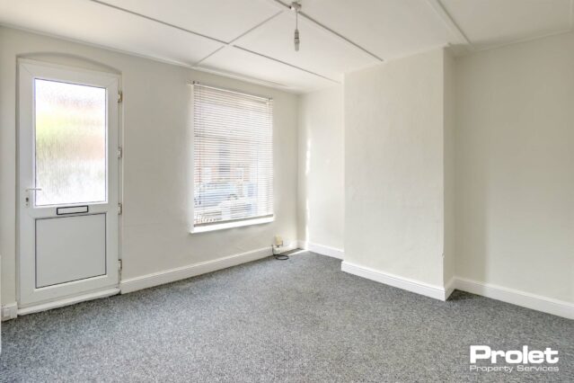 Living room painted white with a UPVC front door.