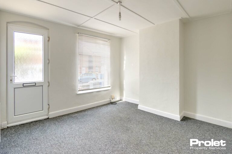 Living room painted white with a UPVC front door.