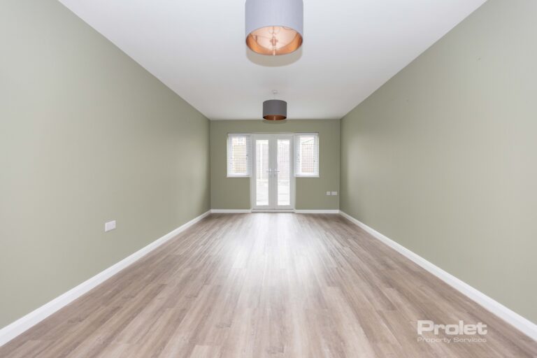 Lounge area with pale green walls, wood effect flooring, and french doors to back garden