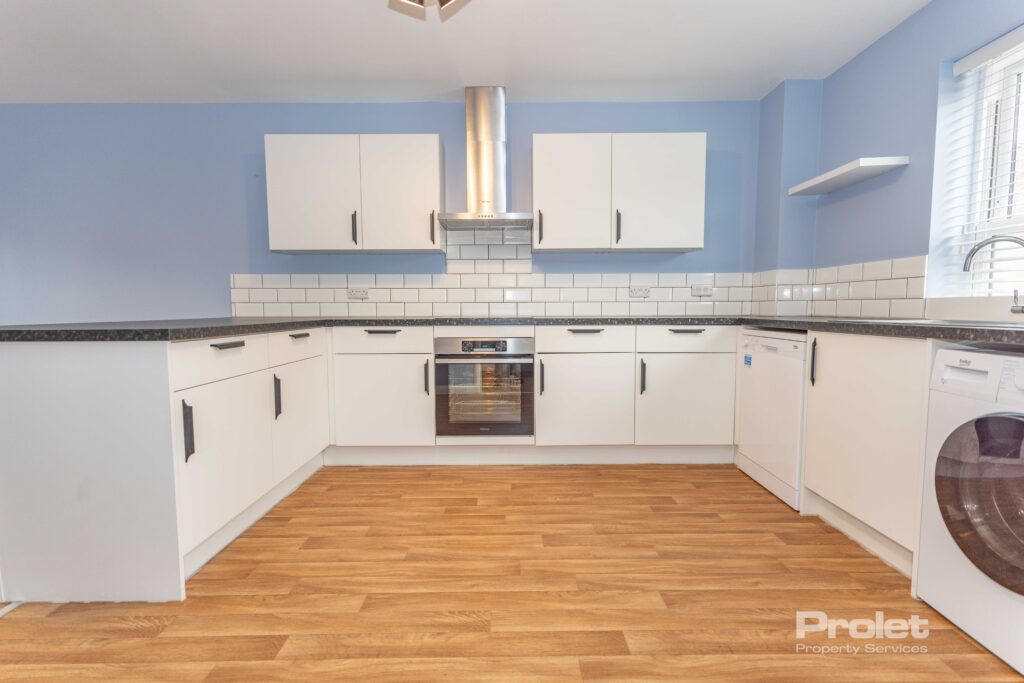 Modern kitchen with white cabinets, black worktop, blue walls, and wood effect flooring. ,