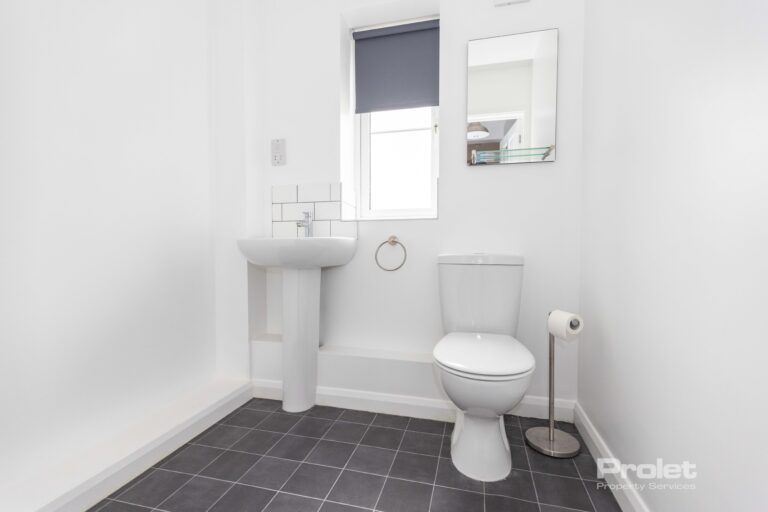 Downstairs WC, with black time flooring, white walls, toilet, and sink