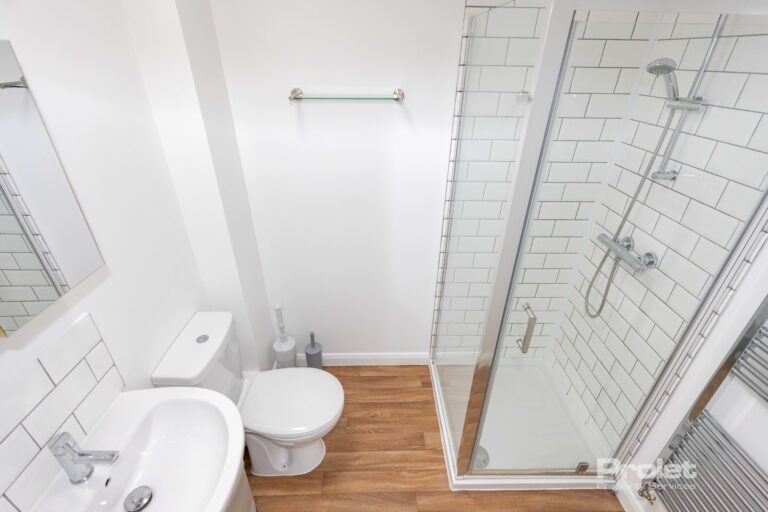 En-suite bathroom with wood effect flooring, shower cubicle, toilet, and sink