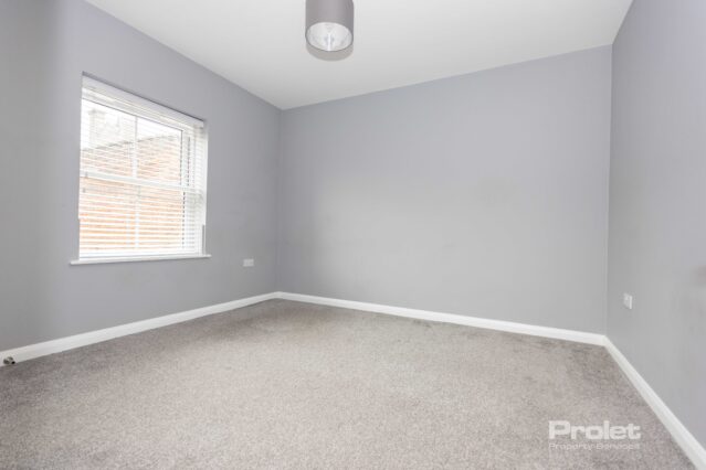 Large double bedroom with grey walls and light carpet.