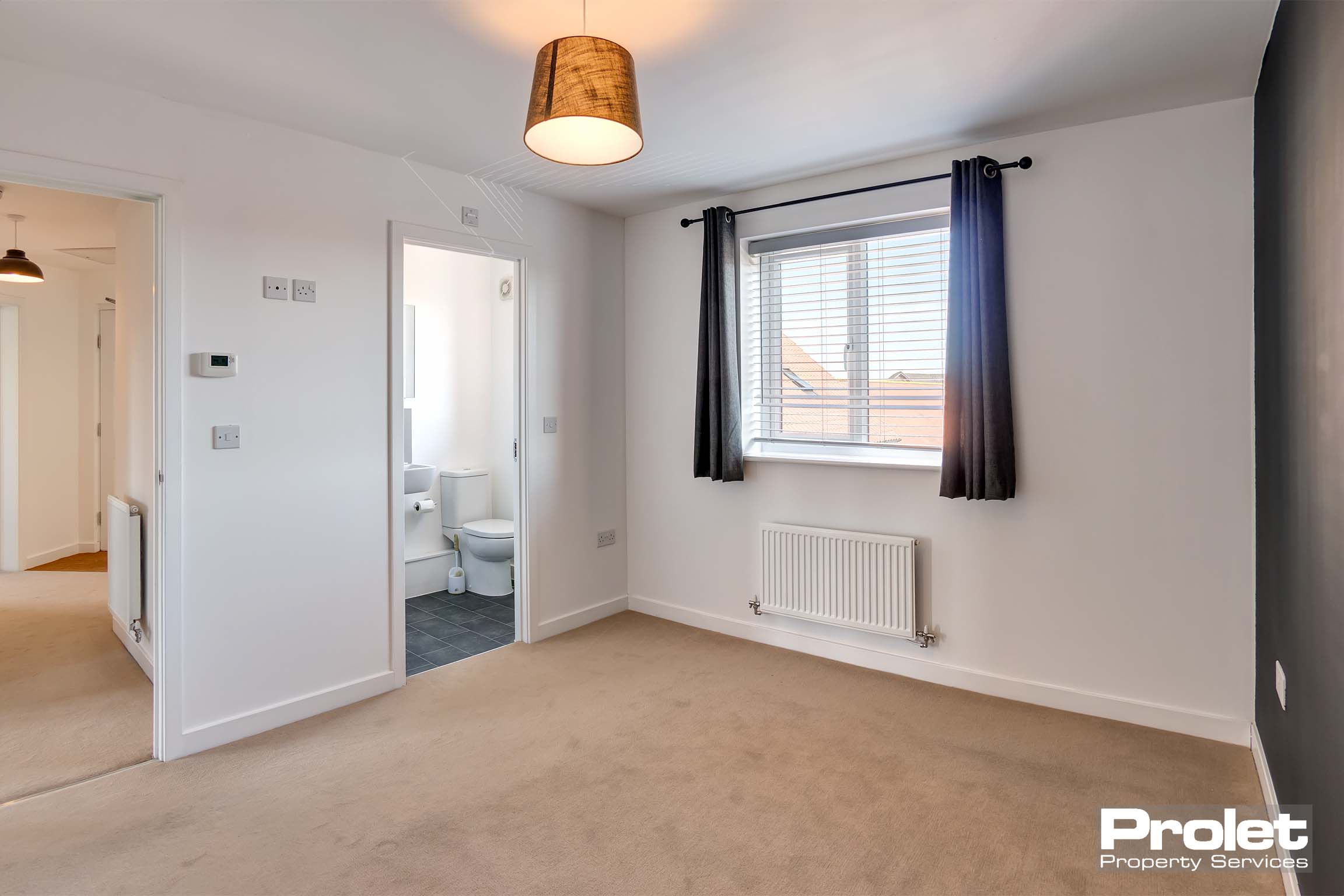 white walls and beige carpet leading off to en suite