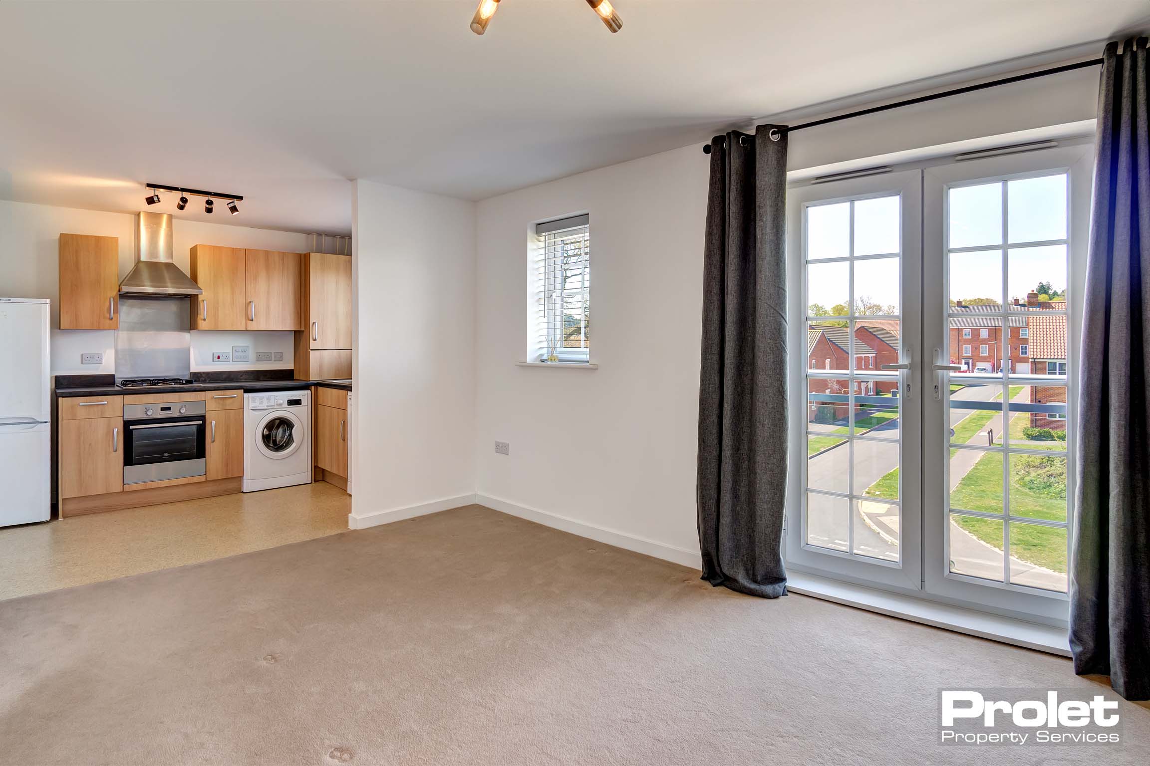 Beige carpet and white walls with juliette balcony and open plan kitchen