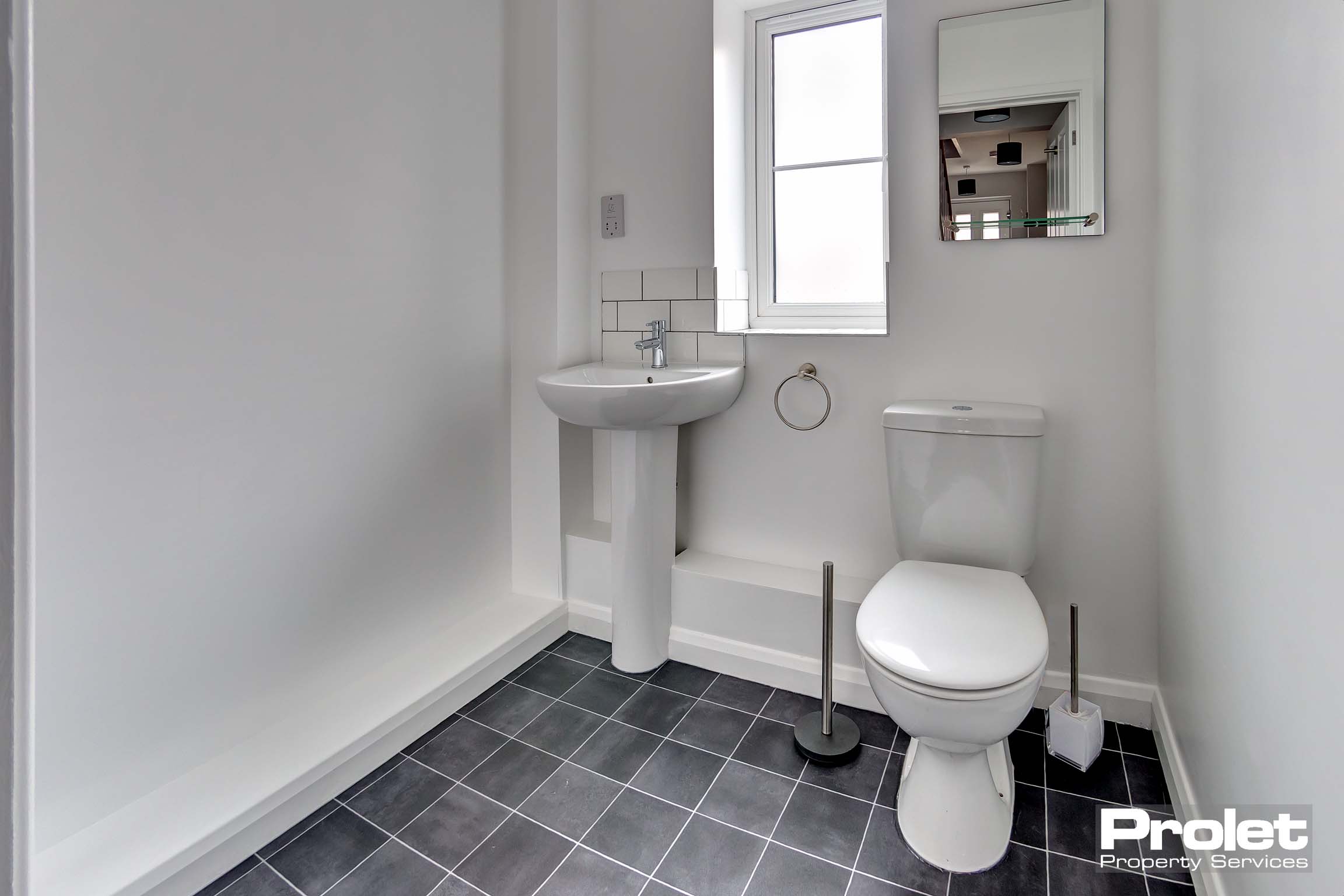 WC with toilet, sink, and black tiled floor