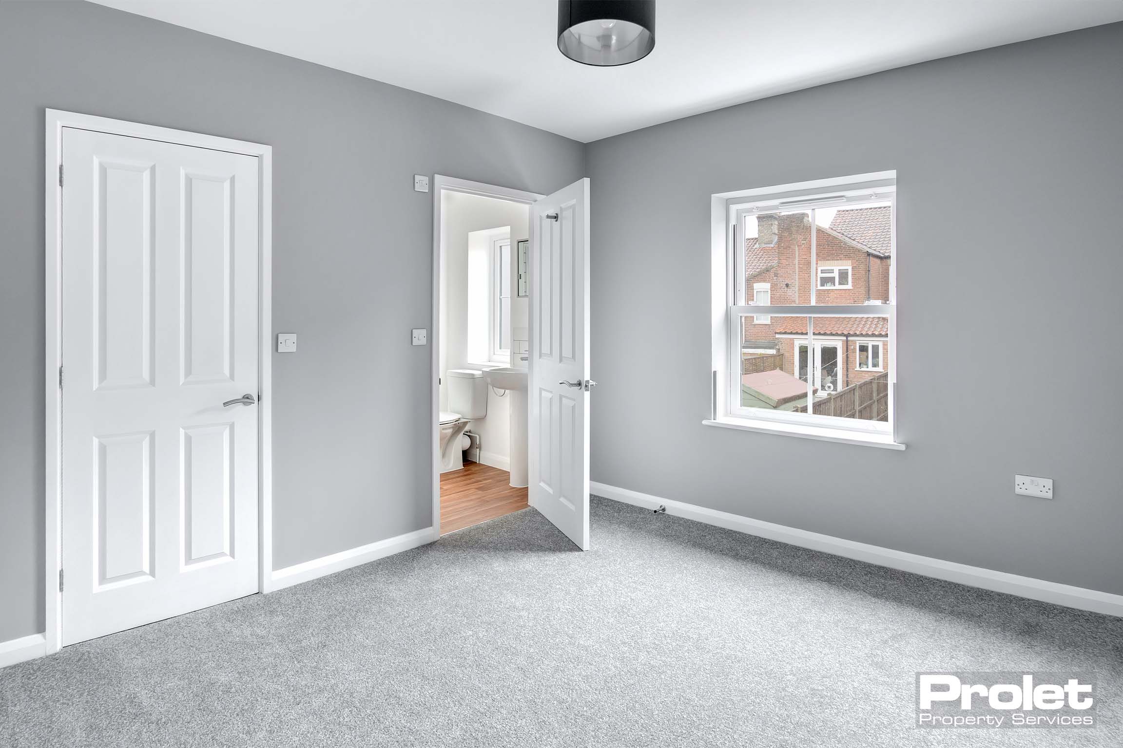 Large double bedroom with grey walls and carpet. Leads to en-suite bathroom