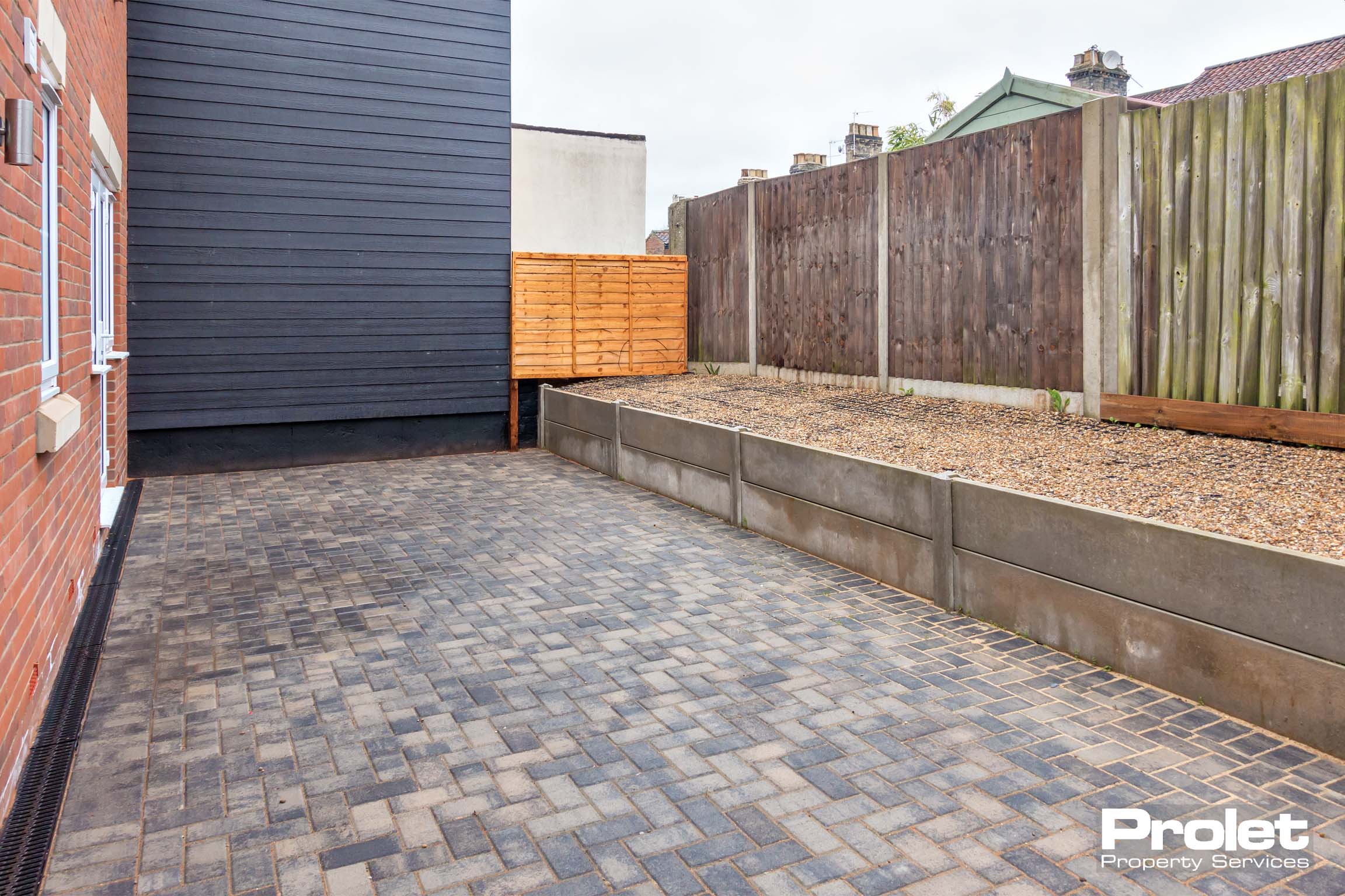 Large paved patio with gravel filled flowerbed