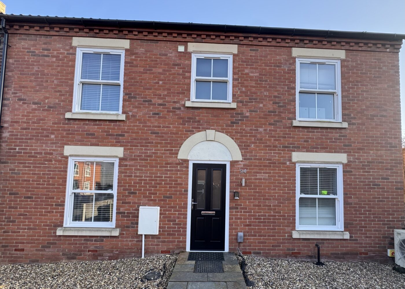 Large red brick end of terrace house, with black front door