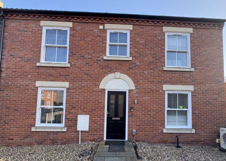 Large red brick end of terrace house, with black front door