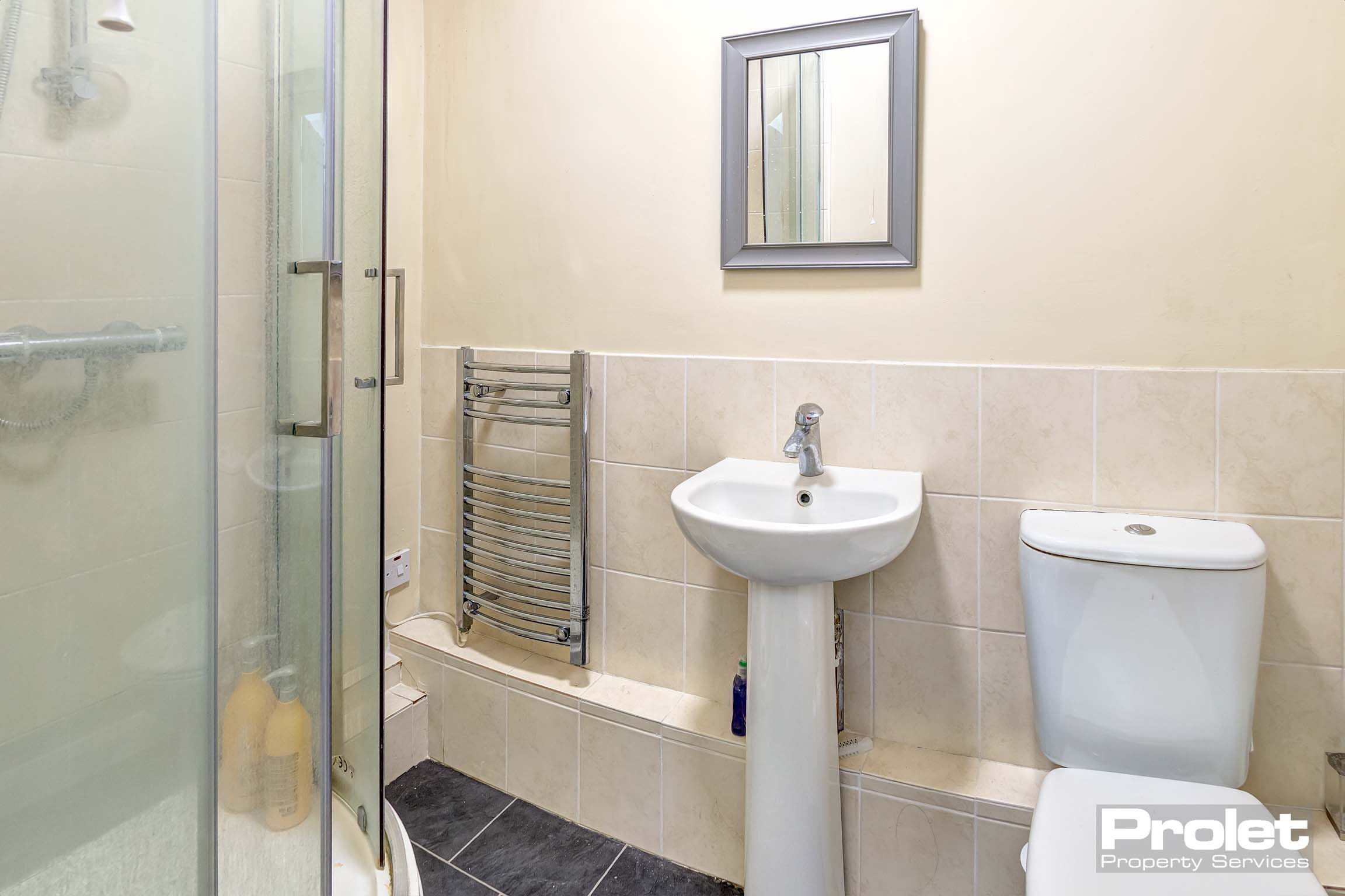 En-suite bathroom with shower cubicle, toilet, sink, and towel warmer