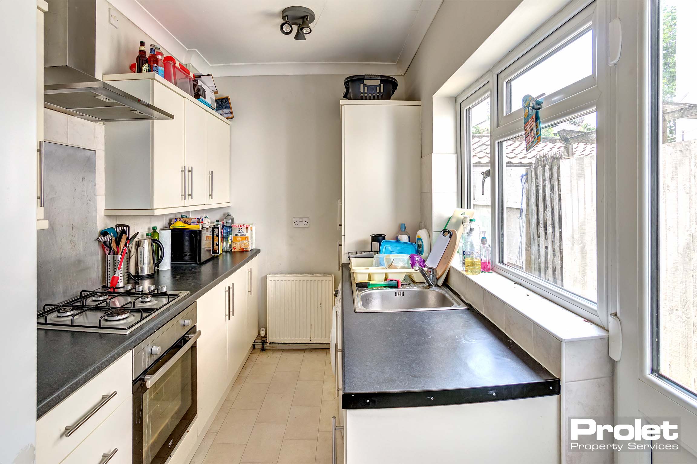 Galley kitchen with white cabinets and black worktops