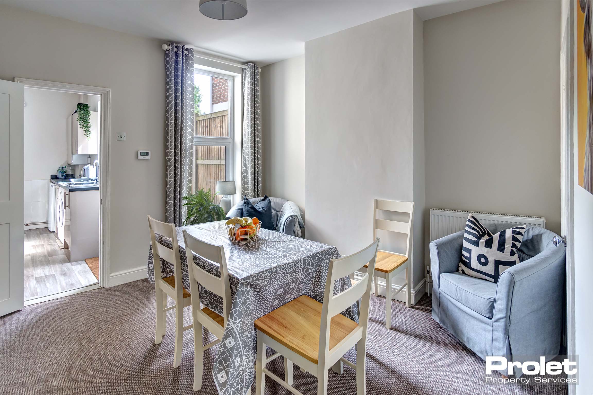 Dining space with a wooden dining table and wooden chairs. A blue fabric chair in the corner of the room.