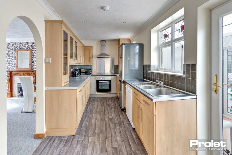Modern galley style kitchen with wood effect units and white goods