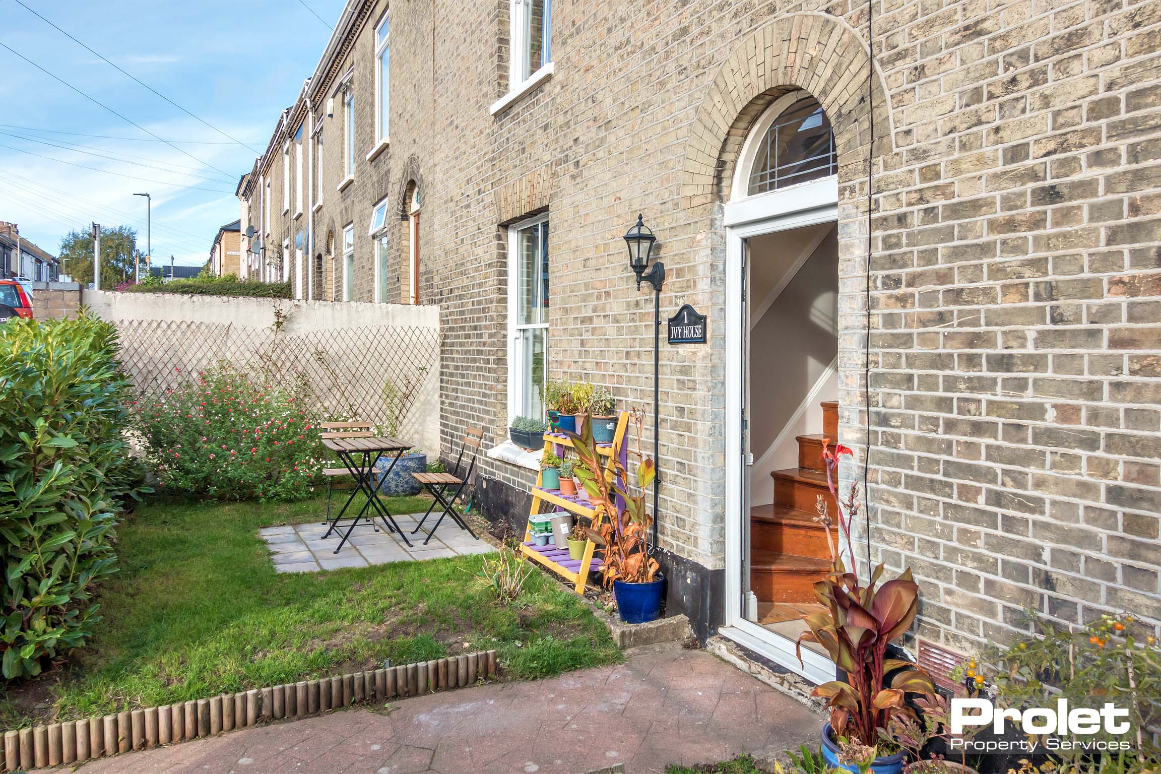 Front garden with small paved area, grass lawn, and hedges