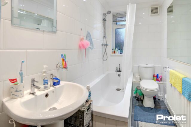 Bathroom with shower over bath, sink, and toilet