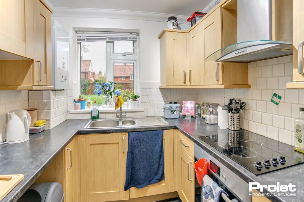 Kitchen with wooden cabinets and black worktops