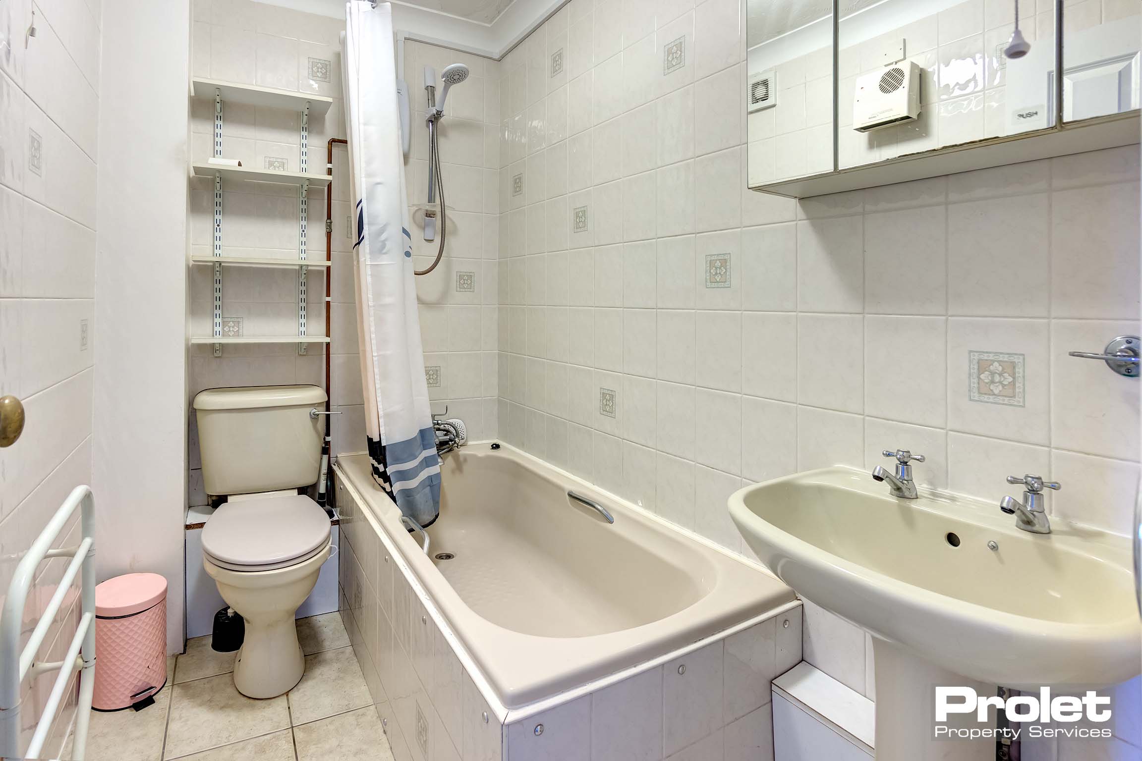 Cream floor tile with off white bath with shower over. W.C and sink.