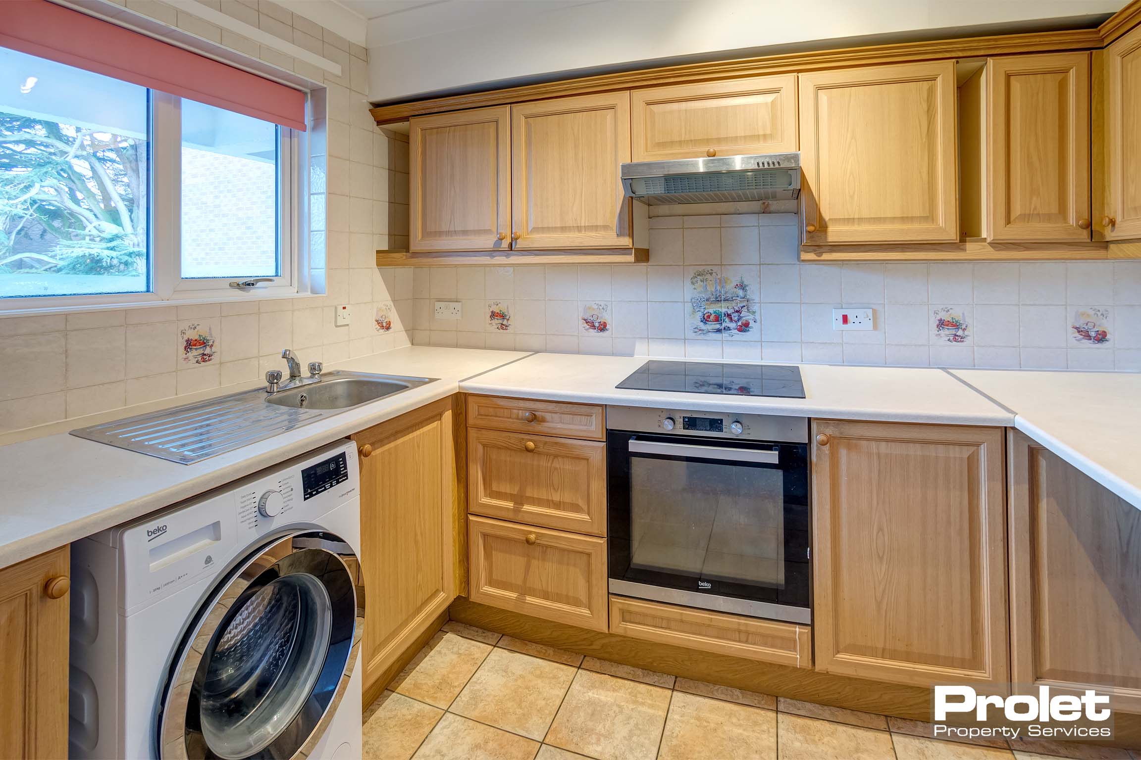 Beige tiled floor tiles with wooden units. Oven, washing machine and fridge freezer included.