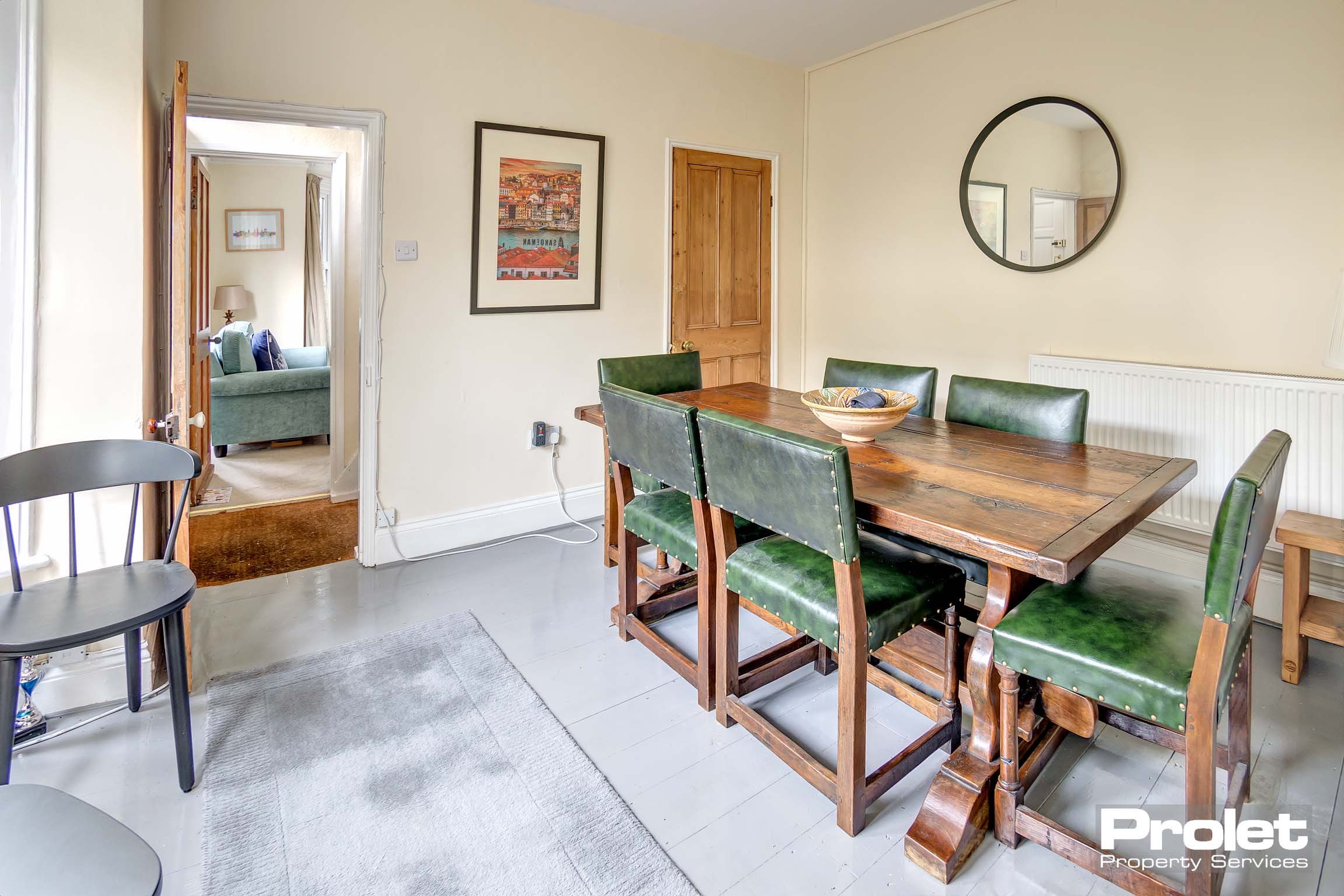 Dining room with painted floor boards and magnolia walls with understairs storage cupboard