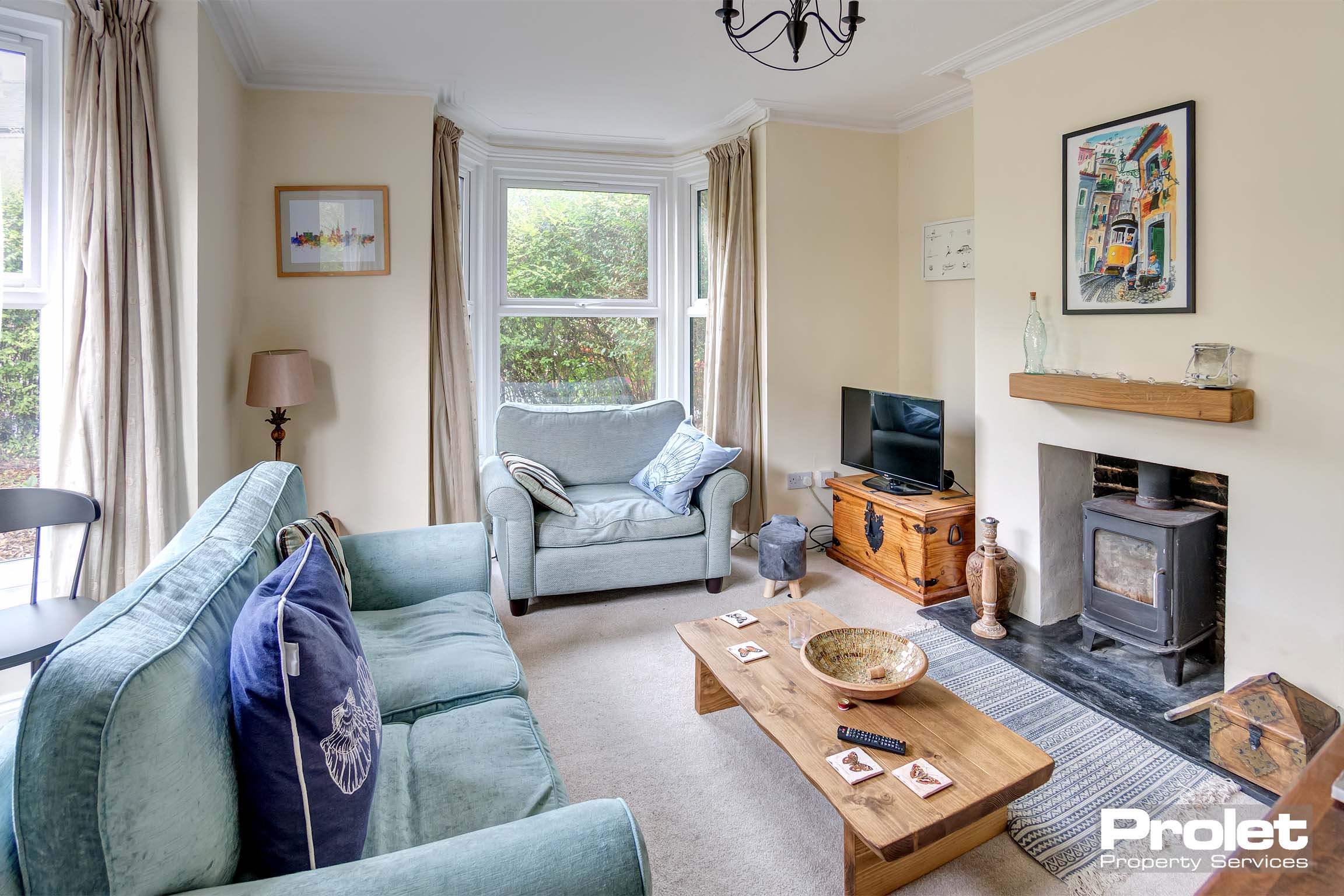 Beige carpet, magnolia walls, wood burner and windows to two walls
