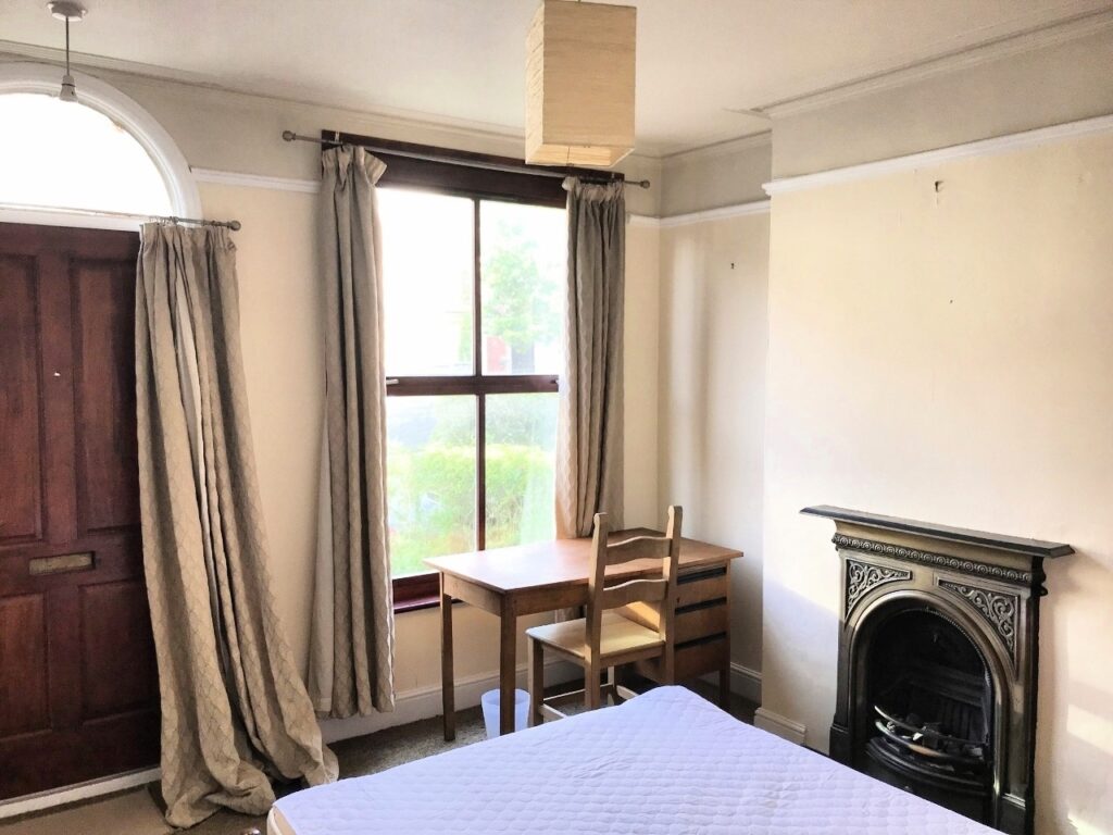 Bedroom with double bed, desk, and period fireplace