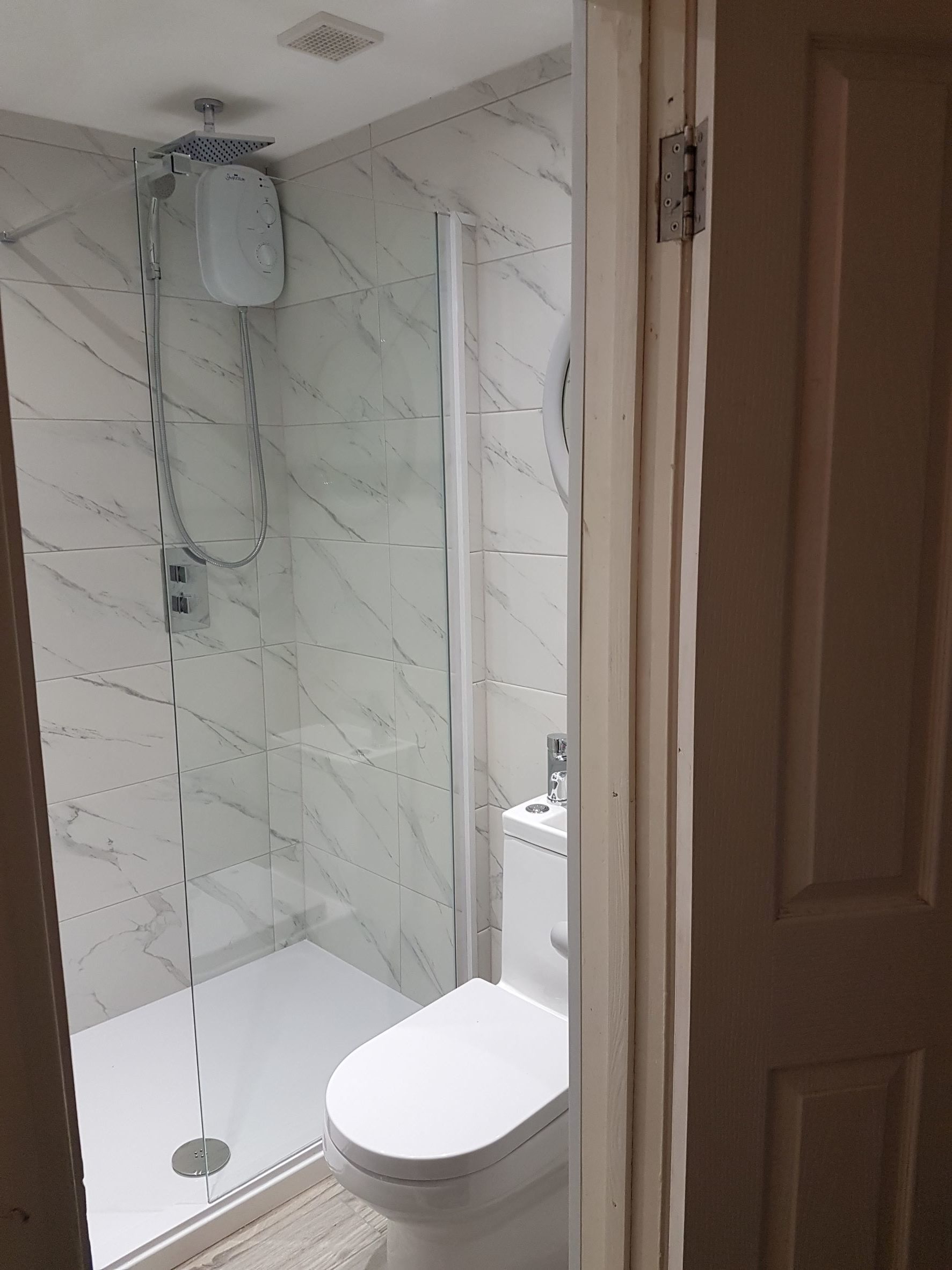 Bathroom with white toilet and sink with a walk in shower.